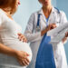 Pregnant female looking at paper with medical prescriptions held by her therapeutist