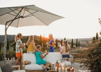 Small group of women are watching the sunset from the garden of their villa on holiday.