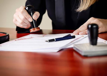 Closeup on notary's public hands stamping document. Notary public accessories