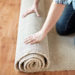 repair, building and home concept - close up of male hands rolling carpet