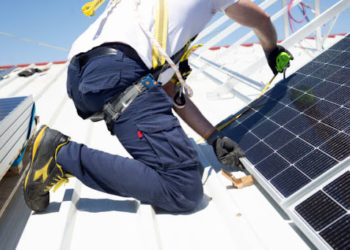 A worker measures solar panels with a meter to install them on the rooftop