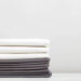 A stack of gray and white bed linens, sheets on the table.